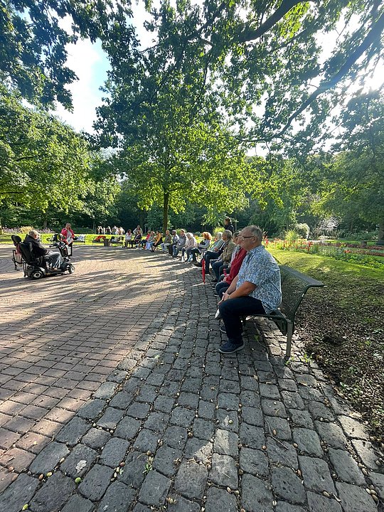 Teilnehmende sitzen auf Bänken