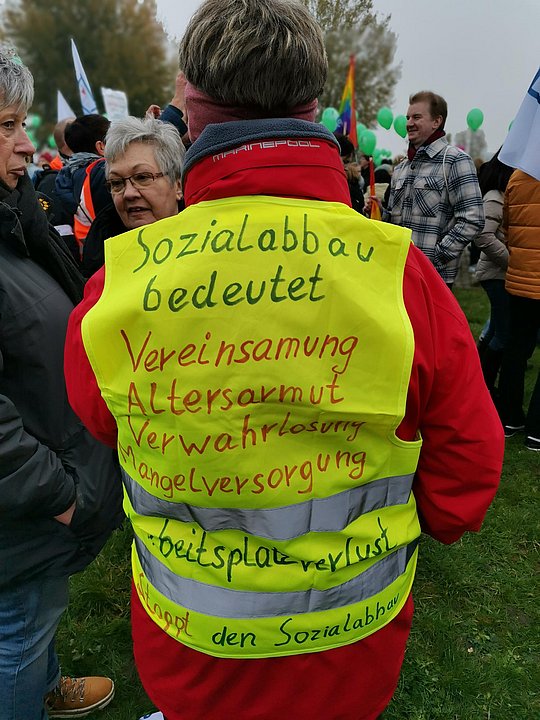 Mensch mit Warnweste, auf der Forderungen stehen